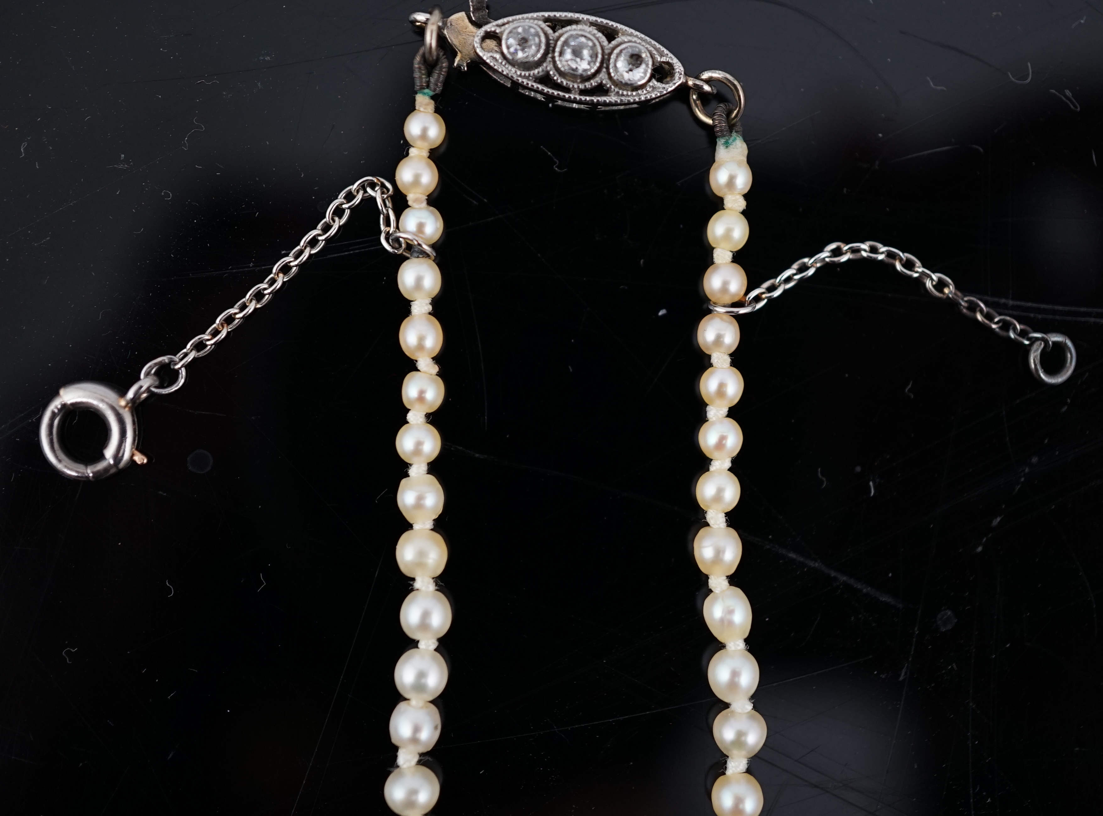 An early 20th century single strand graduated natural pearl and seed pearl necklace, with three stone diamond set clasp and Anchor Cert report dated 27/6/2014 stating an extensive sample to be natural pearls